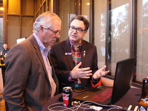 UA President Robert C. Robbins and Professor Moe Momayez talking about what is being displayed on a laptop screen in front of them.