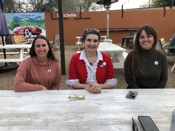 Becky Pallack, Aileen Dingus, and Renée Bidegain sitting at a table, smiling at the camera.