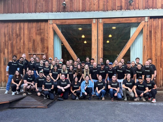 The NeuroID team posing for a picture outside of a wooden building.