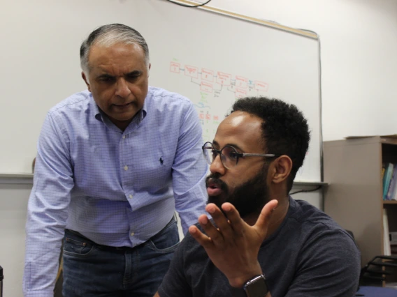 Abhijit Mahalanobis (standing on the left), in discussion with doctoral student Natnael Daba, sitting to his right.