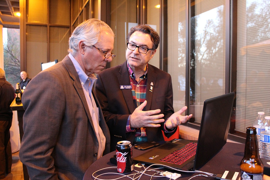 UA President Robert C. Robbins and Professor Moe Momayez talking about what is being displayed on a laptop screen in front of them.