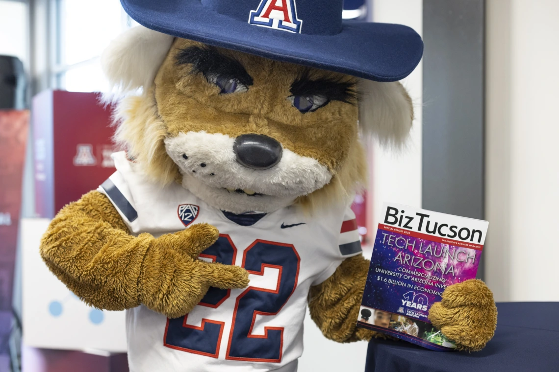 Wilbur Wildcat holding BizTucson magazine. 