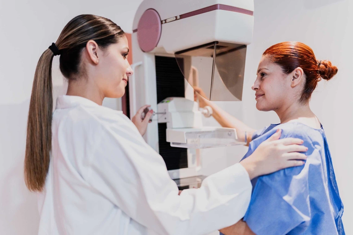 Image of a healthcare provider with a patient in front of a mammography machine.