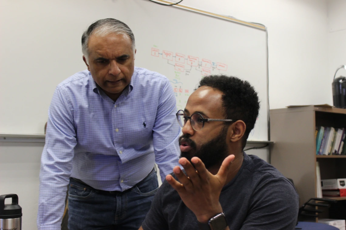 Abhijit Mahalanobis (standing on the left), in discussion with doctoral student Natnael Daba, sitting to his right.