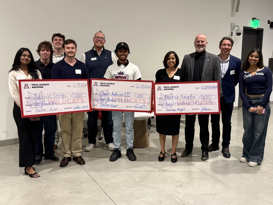 Startup Wildcats and Tech Launch Arizona staff pose with students who have won milestone funding checks at a 2025 Startup Night pitch competition. 