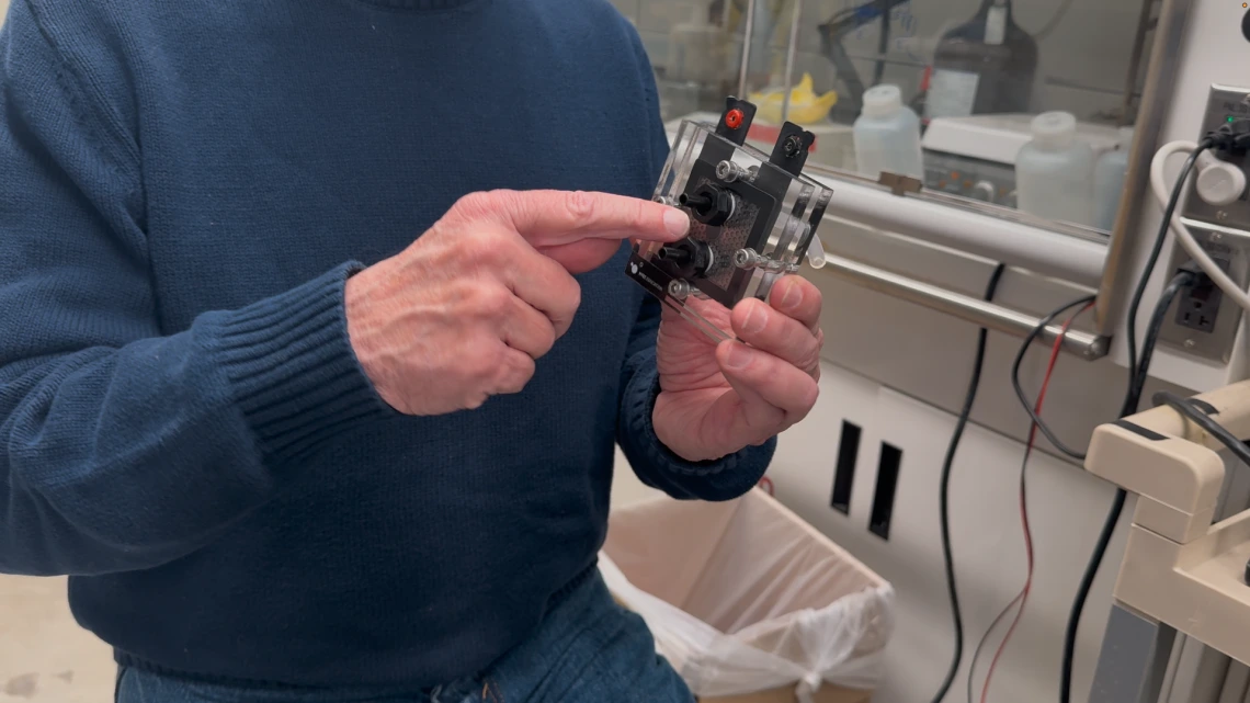 Professor Emeritus Dennis Lichtenberger demonstrates a device he and his team invented that uses a low-cost polymer catalyst to dramatically improve hydrogen production rates in electrolysis systems. 