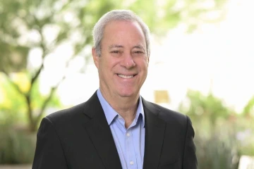 A headshot of Dr. Eric Reiman outdoors with trees in the background.